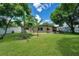 Lush backyard with palm trees, green grass, and a patio area with a grill at 1725 Marcia Dr, Orlando, FL 32807