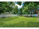 Spacious backyard with green grass, mature trees, and a white fence around the perimeter at 1725 Marcia Dr, Orlando, FL 32807