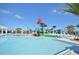 Expansive community pool with a splash pad, seating and mature landscaping under blue skies and a few clouds at 1864 Nice Ct, Kissimmee, FL 34747