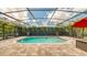 Inviting screened-in pool features beautiful brick pavers, lush landscaping, and a red umbrella at 203 Red Bud Ct, Lake Mary, FL 32746