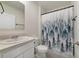 Clean bathroom with a white vanity, toilet, and a stylish forest-themed shower curtain at 2827 Turnstone Run, Harmony, FL 34773