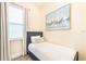 Inviting bedroom with a single bed, nautical artwork, wood-look tile flooring, and natural light at 2978 Latitude Ln, Kissimmee, FL 34747