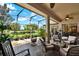 This covered lanai has stone floors, ceiling fans, and comfortable seating with beautiful golf course views at 313 Sorrento Rd, Poinciana, FL 34759