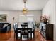 Dining area showcases a modern chandelier, sleek black table set, and shiny hardwood flooring at 3536 Moss Pointe Pl, Lake Mary, FL 32746