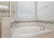 Bright bathroom featuring a soaking tub with decorative tile accents, and a large window at 5290 Citrus Leaf Blvd, Winter Garden, FL 34787