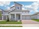 Modern two-story home with a brick driveway, covered porch, metal roof and neutral-tone exterior paint at 5307 Citrus Leaf Blvd, Winter Garden, FL 34787