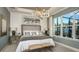 Elegantly designed primary bedroom with a tray ceiling, decorative lighting, and a large window at 556 Moon Shell Cir, New Smyrna Beach, FL 32168