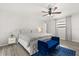 Bright bedroom with ceiling fan, large bed, blue chaise, and wood-look floors at 7 Forest Ln, Eustis, FL 32726