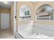 Bright bathroom featuring a soaking tub with tile surround and decorative windows allowing plenty of natural light at 7672 Torino Ct, Orlando, FL 32835