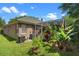 View of backyard and screened lanai, showcasing the home's green roof, A/C units, and landscaping at 7672 Torino Ct, Orlando, FL 32835