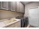 Well-equipped laundry room with modern washer and dryer, ample storage, and utility sink at 7672 Torino Ct, Orlando, FL 32835