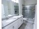 Bathroom featuring a double sink vanity, glass-enclosed shower, and gray accents at 8912 Cabot Cliffs Dr, Davenport, FL 33896