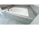 Elegant soaking tub surrounded by gray tile, creating a relaxing spa-like atmosphere at 8912 Cabot Cliffs Dr, Davenport, FL 33896