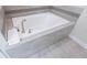 Clean white soaking tub with gray tiled surround and brushed nickel faucet at 8912 Cabot Cliffs Dr, Davenport, FL 33896