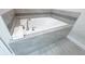 Modern white bathtub with gray tiled surround and brushed nickel fixtures at 8912 Cabot Cliffs Dr, Davenport, FL 33896