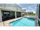 Backyard view of a screened-in pool and spa with a brick paver deck and outdoor seating area at 8912 Cabot Cliffs Dr, Davenport, FL 33896