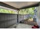 View of a covered patio with gray fencing, concrete flooring, and surrounded by lush greenery at 102 Wild Plum Ln, Longwood, FL 32779