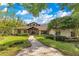Charming home with mature trees, a brick walkway, lush landscaping, and manicured bushes at 10577 Down Lakeview Cir, Windermere, FL 34786