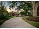 Stately home featuring a grand brick driveway framed by lush landscaping and mature trees at sunset at 10577 Down Lakeview Cir, Windermere, FL 34786