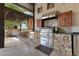 Covered outdoor kitchen equipped with stainless steel grill, pizza oven, and stone countertops at 10577 Down Lakeview Cir, Windermere, FL 34786