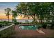 Inviting outdoor pool and patio area with comfortable lounge chairs, overlooking a tranquil lake at sunset at 10577 Down Lakeview Cir, Windermere, FL 34786