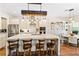 A kitchen island features a white countertop, pendant lighting and seating at the breakfast bar at 11689 Hampstead St, Windermere, FL 34786