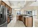 Well-lit kitchen featuring stainless steel appliances, wood cabinetry, and a neutral tile floor at 2425 Rambling Oaks Way, Kissimmee, FL 34746