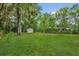 Spacious backyard with lush green lawn, mature trees, a storage shed, and a cozy fire pit area, perfect for outdoor entertaining at 247 S Marydell Ave, Deland, FL 32720