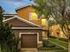 Two-story home featuring a two-car garage, tan and brown stucco, manicured landscaping, and lovely curb appeal at 3166 Rodrick Cir, Orlando, FL 32824