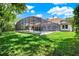 Lush green backyard featuring a screened-in pool area, perfect for outdoor recreation and relaxation at 32613 View Haven Ln, Sorrento, FL 32776