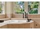 Close up of corner jacuzzi tub under 3 windows with black candles and greenery at 32613 View Haven Ln, Sorrento, FL 32776