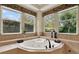 Sunlit bathroom featuring a luxurious jacuzzi tub set against three windows with lush green views at 32613 View Haven Ln, Sorrento, FL 32776