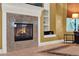 Close-up of a granite fireplace and built-in shelving in the living room, with a tiled floor and natural light at 32613 View Haven Ln, Sorrento, FL 32776