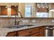 Kitchen sink and countertop featuring granite counters, stainless steel appliances, tile backsplash, and custom wood cabinets at 32613 View Haven Ln, Sorrento, FL 32776