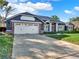 This single-story home showcases a two-car garage, driveway, and brick accents at 4916 Winwood Way, Orlando, FL 32819