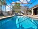 Sparkling screened-in pool, perfect for outdoor entertainment, features a bar, seating, and manicured landscaping at 4916 Winwood Way, Orlando, FL 32819