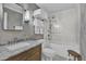 Bright bathroom featuring a marble vanity, decorative wallpaper and a glass enclosed shower-tub combo at 5205 Saint Regis Pl, Belle Isle, FL 32812