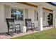Inviting front porch featuring comfortable rocking chairs, stylish pillows and exposed beam ceiling at 5205 Saint Regis Pl, Belle Isle, FL 32812