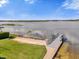 Scenic lake view from the shoreline with a dock, sandy beach, and lush green grass at 5205 Saint Regis Pl, Belle Isle, FL 32812