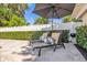 Relaxing poolside scene with comfortable lounge chairs and a shade umbrella in a fenced in back yard at 5205 Saint Regis Pl, Belle Isle, FL 32812