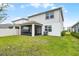 Backyard view of a two story home with a screened in patio, lush green grass and blue skies at 5329 Royal Point Ave, Kissimmee, FL 34746