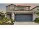 Front exterior of a two-story home with a gray garage door and landscaped yard at 5329 Royal Point Ave, Kissimmee, FL 34746