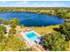Aerial view of pool near the lake with lounge chairs, picnic tables, and trees around the property at 5402 Kingswood Dr, Orlando, FL 32810