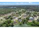 Scenic aerial view of a neighborhood nestled among lush trees and a tranquil lake under a partly cloudy sky at 549 Mcneal Dr, Deltona, FL 32725