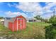 View of a red painted shed with a brown shingle roof at 549 Mcneal Dr, Deltona, FL 32725