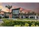 Stunning exterior of the clubhouse with modern architecture and palm trees against a colorful sunset sky at 5663 Loggia Ln, Kissimmee, FL 34758
