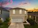 Charming two-story home with a well-maintained lawn and a two-car garage, set against a colorful evening sky at 715 Chinoy Rd, Davenport, FL 33837