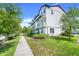 A side view of the townhouse, landscaped with lawn and bushes, as well as a sidewalk lined with trees at 7772 Sweet Star Avenue, Orlando, FL 32836