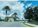 Community entrance gate surrounded by lush landscaping and palm trees under a bright blue sky at 8023 King Palm Cir, Kissimmee, FL 34747