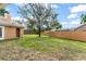 Spacious fenced backyard featuring a lush green lawn with a large tree providing shade and a screen enclosed patio at 836 Copperfield Ter, Casselberry, FL 32707